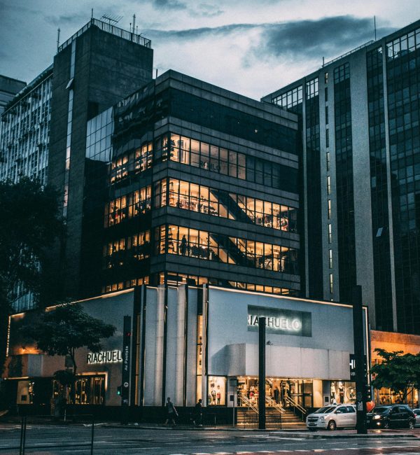 pexels-photo-65438-65438 Night view of a city block with illuminated store, modern architecture, and cloudy sky.